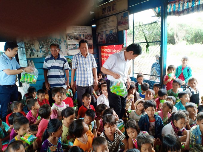Đồng chí Giám đốc Học viện và các thành viên đoàn tặng quà cho các em học sinh nghèo Việt Nam tại Biển Hồ