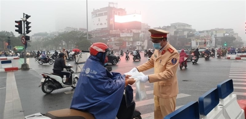 Trời mưa lất phất, tất cả người tham gia giao thông phải mặc áo mưa khi di chuyển, nhưng các chiến sĩ vẫn đứng ngoài đường phát khẩu trang miễn phí cho người dân.