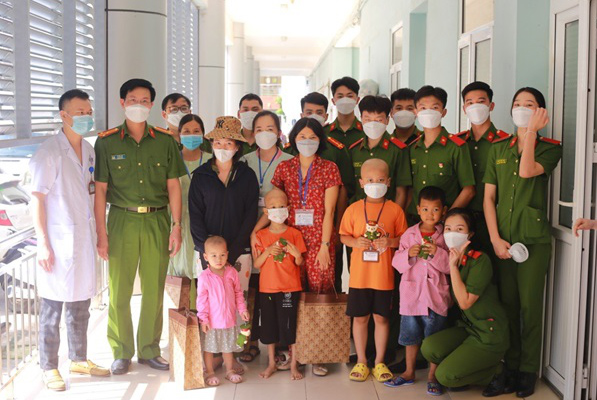 Thượng tá, PGS. TS Lê Hữu Anh (thứ hai, bên trái) - đại diện khoa Kỹ thuật hình sự - động viên, thăm hỏi gia đình các bệnh nhi tại Bệnh viện K Tân Triều
